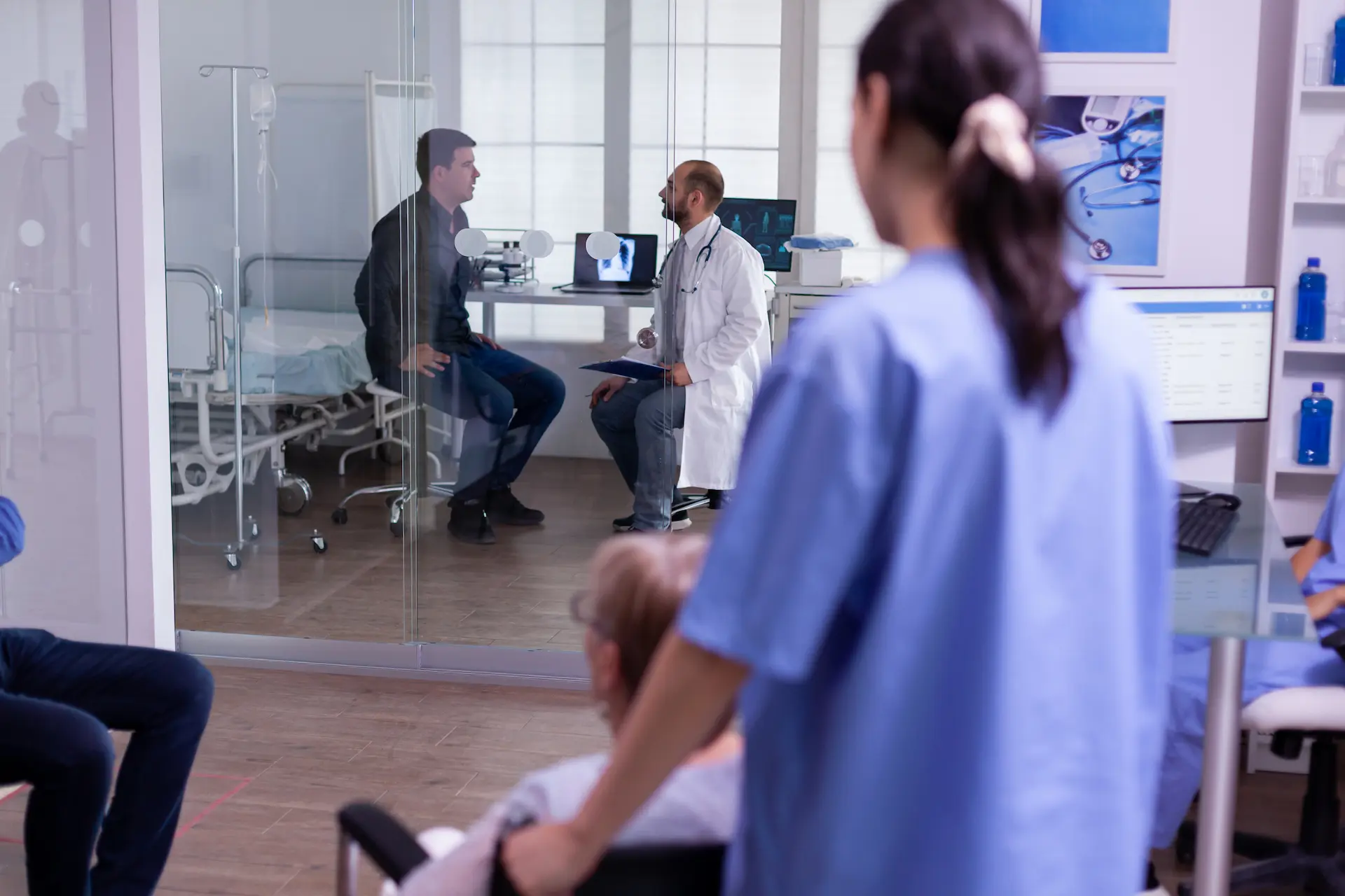 Assistente medico spinge una paziente anziana in sedia a rotelle nel corridoio del centro polispecialistico