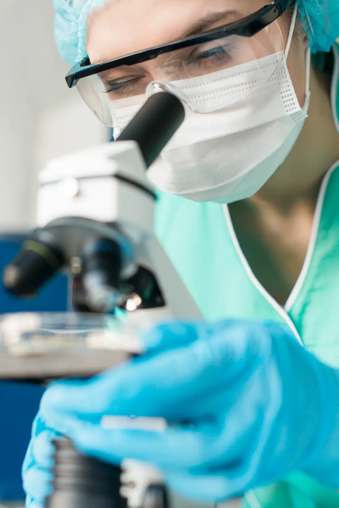 Medico ricercatore o tecnico di laboratorio che esamina un vetrino al microscopio per analisi mediche nel centro polispecialistico