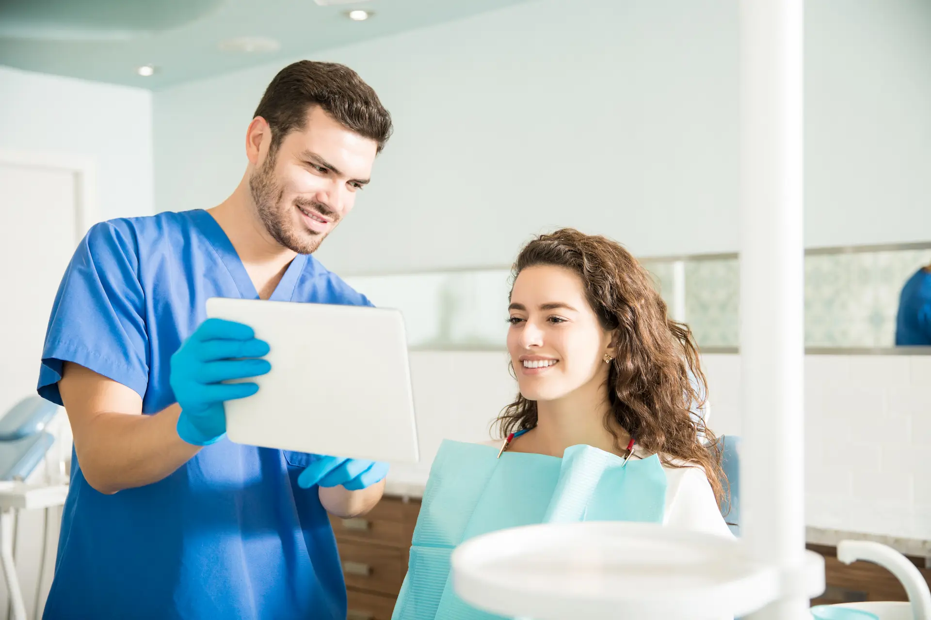 Dentista mostra il piano di trattamento dentale personalizzato su un tablet alla paziente sorridente